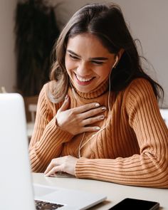 a woman smiles as she uses her laptop