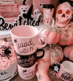 someone is holding a coffee mug in front of some pink decorations and skulls on the table