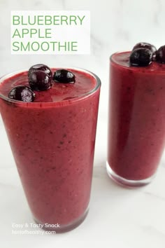 two glasses filled with blueberry apple smoothie on top of a white marble counter