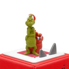 the grinch toy is sitting on top of a red box with shark fin handles