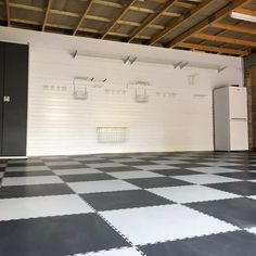 an empty garage with black and white checkered flooring, refrigerators and cabinets