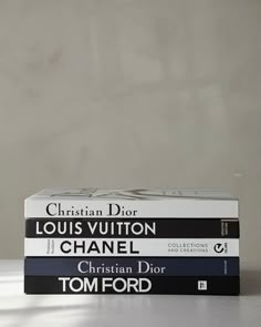 three books stacked on top of each other in front of a white wall and floor