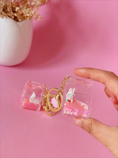 a person holding a keychain with a small animal in it on a pink surface