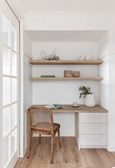 a chair sitting in front of a desk with shelves on the wall and bookshelves above it