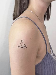 a woman's shoulder with a small tattoo of a person sitting in a lotus position