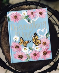 a book sitting on top of a wooden table next to a metal rack filled with flowers