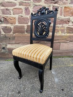 an antique chair sitting in front of a brick wall on the side of a road