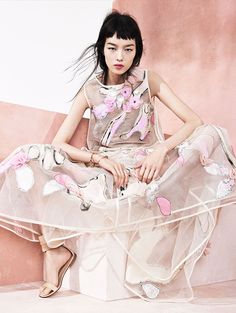 a woman sitting on top of a chair wearing a dress and high heeled shoes