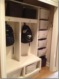 an organized mudroom with white shelves and storage bins