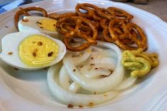 an egg, onion rings and pretzels on a plate