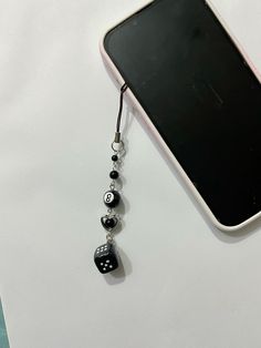 a cell phone with a black and white beaded charm hanging from it's side