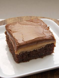 a piece of chocolate cake sitting on top of a white plate with a wooden table in the background