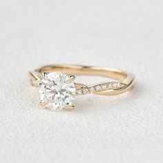 a gold engagement ring with a round diamond on the side and pave set diamonds around the band