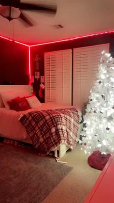 a bedroom decorated for christmas with red lights and a white tree in the corner next to the bed