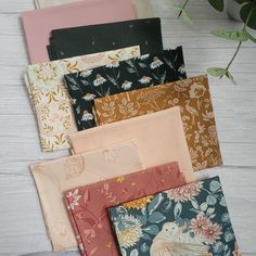 six different colors of fabric with flowers and birds in them on a white wooden surface