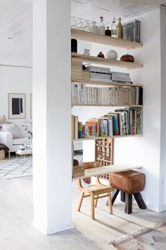 a living room filled with furniture and bookshelves next to a doorway that leads into a bedroom