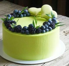 a green cake with berries and leaves on top