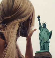 a woman with headphones looking at the statue of liberty in new york, ny