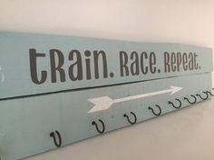 a wooden sign that says rain race repeat and an arrow pointing to the right on a white wall