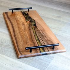 a wooden cutting board with two black handles on the top and one is made out of wood