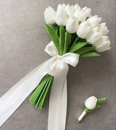 a bouquet of white tulips tied to a satin ribbon with a flower on the side