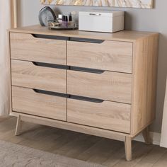 a wooden dresser with drawers in front of a painting