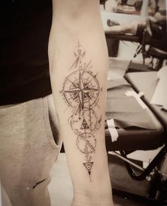 a man's arm with a compass tattoo on it