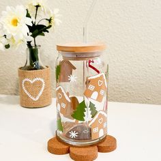 a glass jar filled with gingerbread cookies next to a flower vase and cork coasters