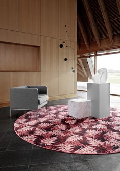 a living room with an area rug, chair and table in the middle of it