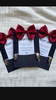 four red bow ties are attached to black suspenders with white cards on the bottom