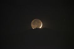 the moon is visible in the dark night sky