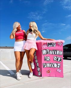 two beautiful women standing next to each other near a pink sign that says my battle is so fierce