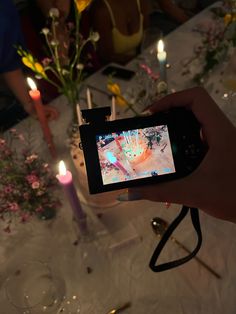 a person holding up a cell phone to take a photo with candles and flowers in the background