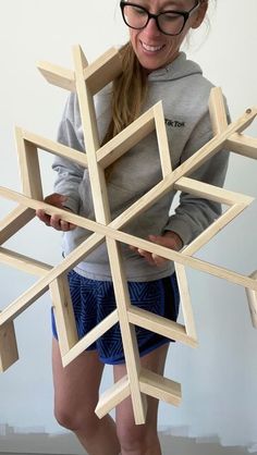 a woman is holding a wooden snowflake