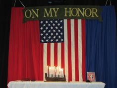 a cake with lit candles on it sitting in front of an american flag and banner