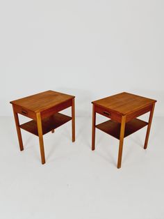 two small wooden tables sitting next to each other on a white surface with no one around them