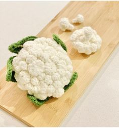 there is a piece of cauliflower on the cutting board next to two pieces of broccoli