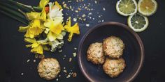 flowers and lemons on a table next to pastries with oats in them