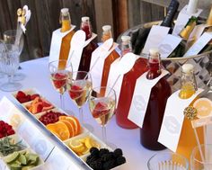 a table topped with lots of bottles of wine and glasses filled with different types of fruit