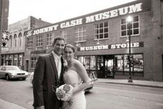 a man and woman are standing in front of a museum on the side of the road