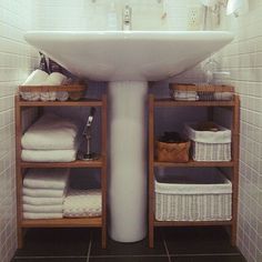 a white sink sitting under a bathroom mirror next to a shelf filled with folded towels