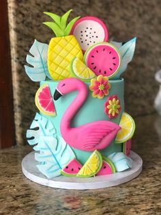 a cake decorated with fruit and a pink flamingo sitting on top of a counter