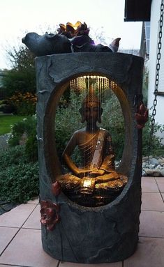 a buddha statue sitting in the middle of a garden with lights on it's sides