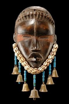 an african mask with bells hanging from it