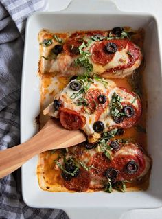 two pieces of pizza in a white casserole dish with a wooden spatula