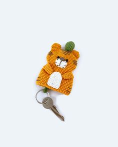 an orange teddy bear with a green hat on it's head is holding a key chain