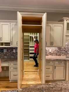 a woman is standing in the open door to her new kitchen, while another person stands at the end of the room