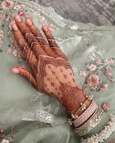 a woman's hand with henna and bracelets on top of her arm