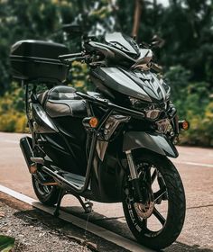 the motorcycle is parked on the side of the road next to some bushes and trees