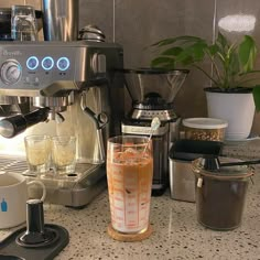 a coffee maker sitting on top of a counter next to cups and containers filled with liquid